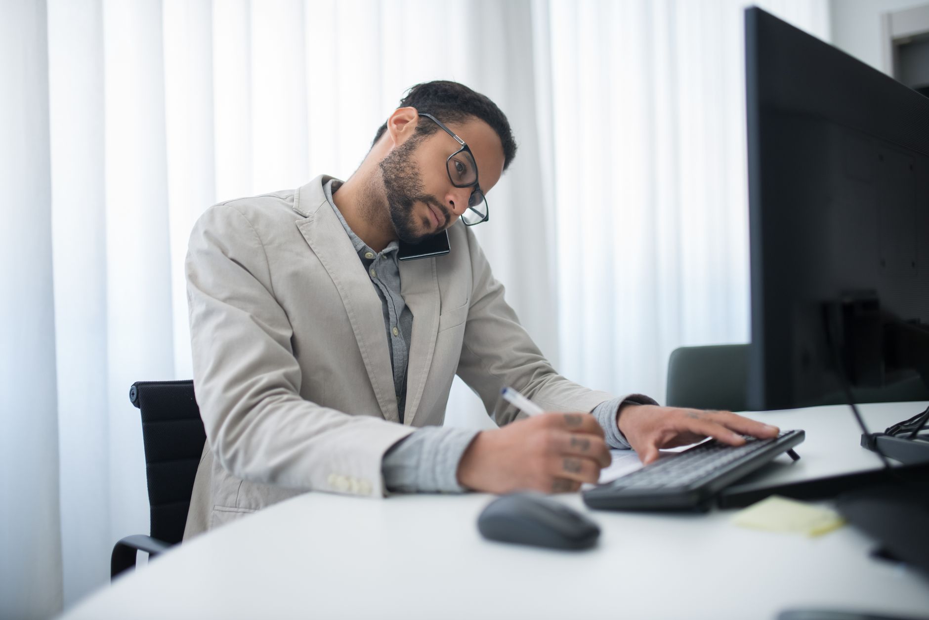 an office worker slouched in a chair, pressing one hand against his lower back in discomfort