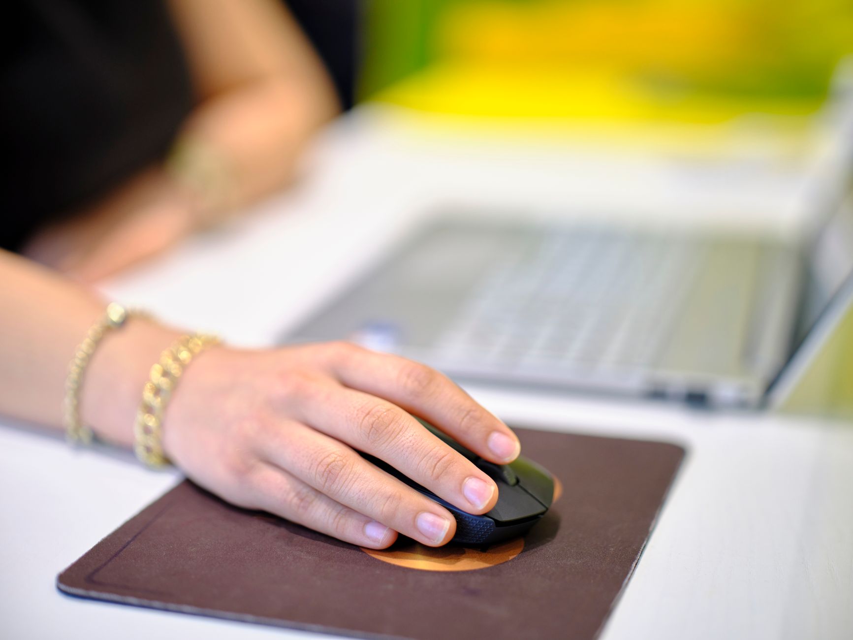 A person's hand holding a black vertical ergonomic mouse at an office desk.