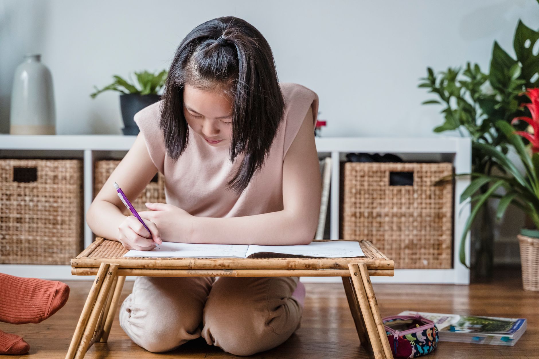 Person kneeling at a folding floor desk with a tilted top holding an open laptop