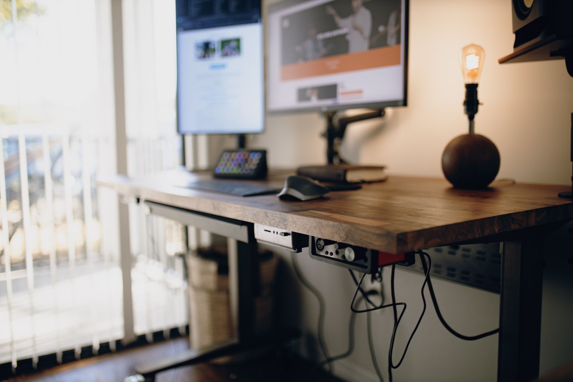 a person adjusting a monitor arm at an adjustable standing desk