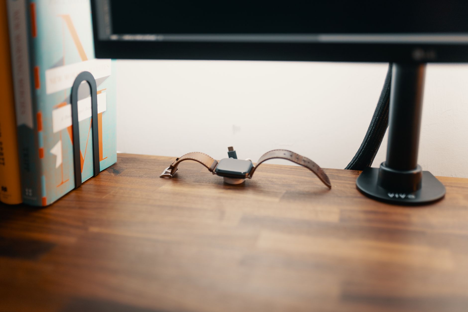 Black cable spine wrapped around monitor and power cables under a standing desk